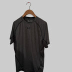 Gray t-shirt with Under Armour logo on a wooden hanger against a white wall.