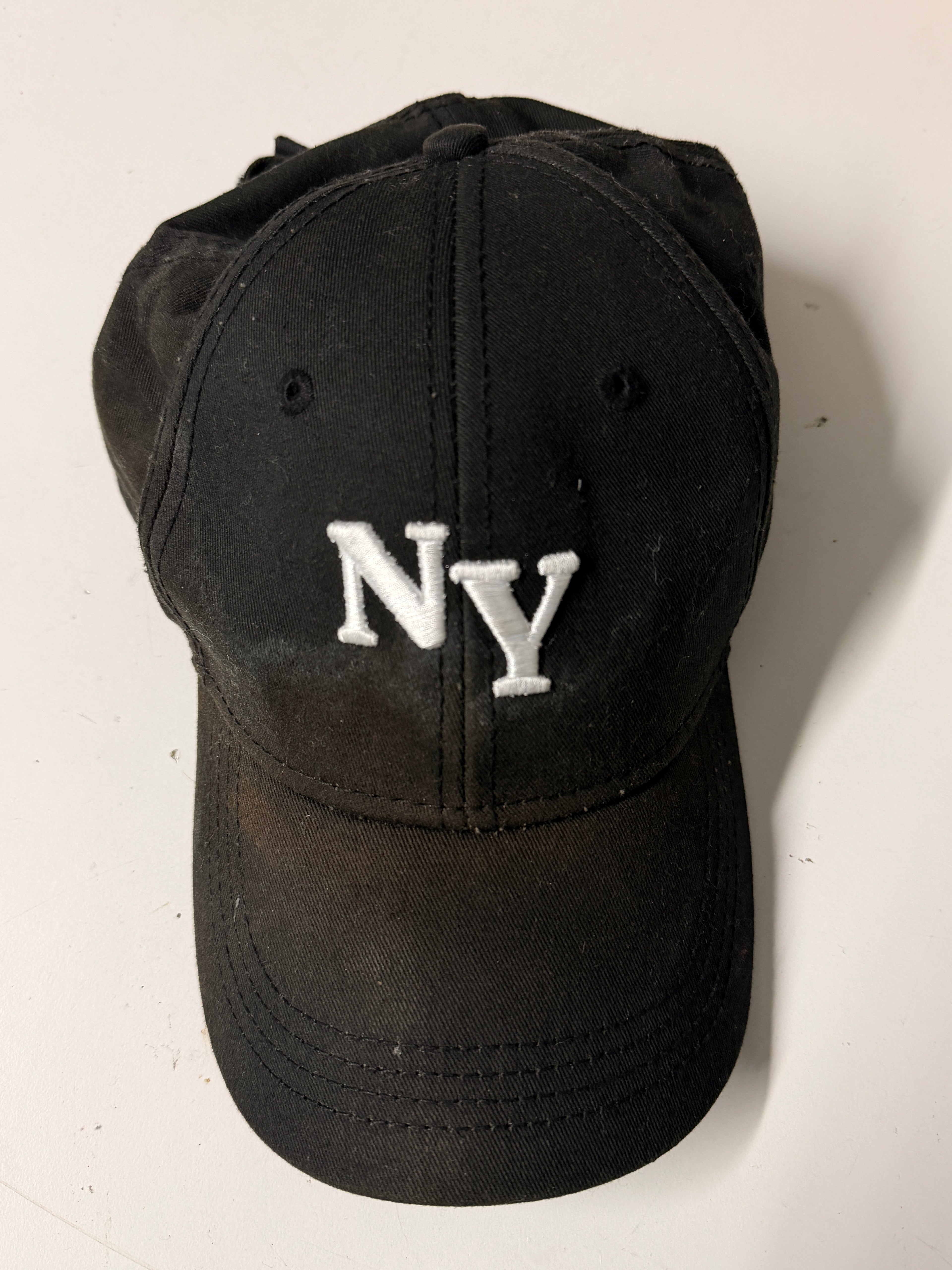 Black cap with 'NY' embroidered on a white background