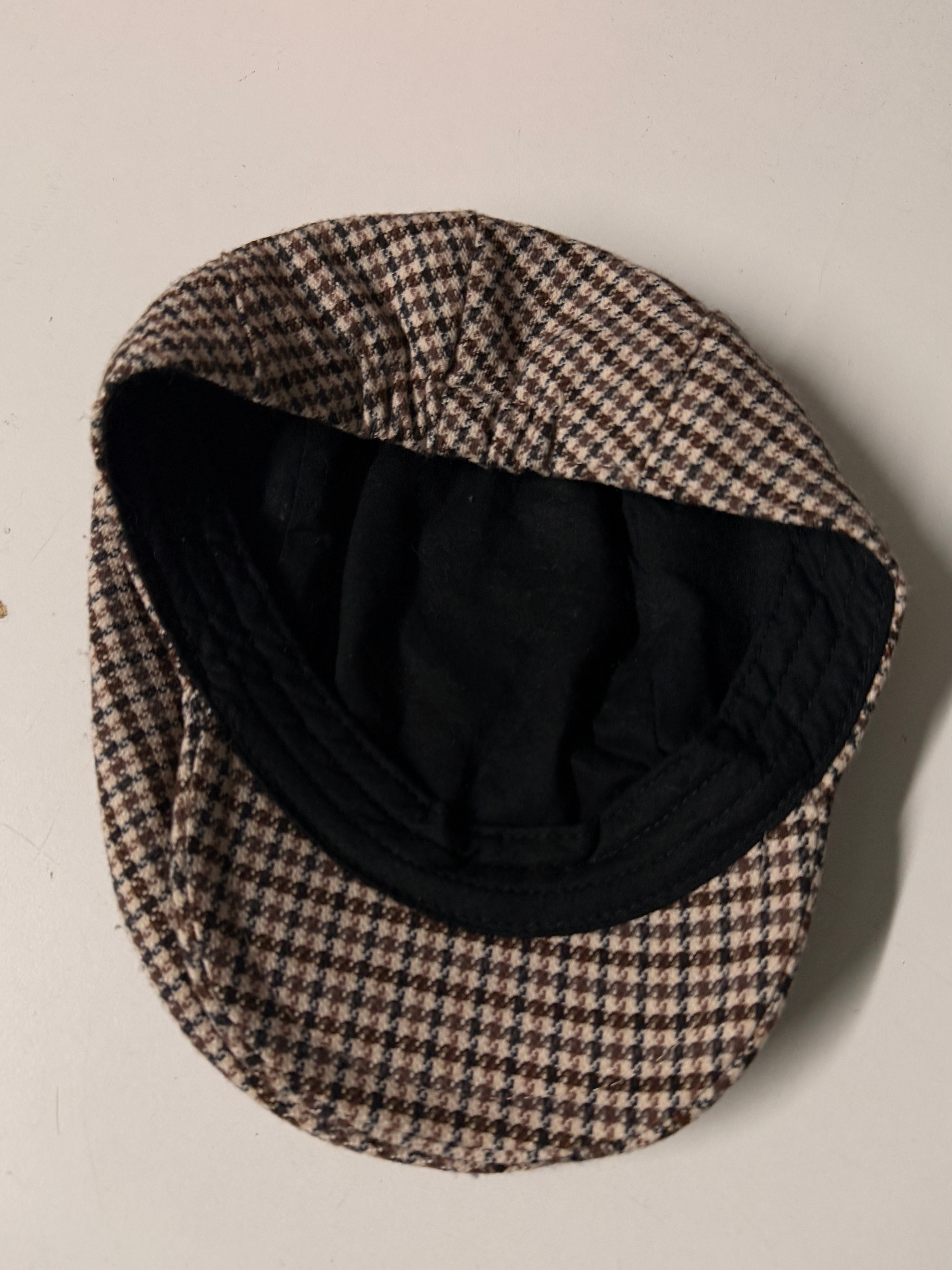 Houndstooth patterned hat with black interior on a beige background