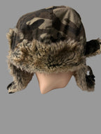 Camouflage hat with fur trim on a white surface