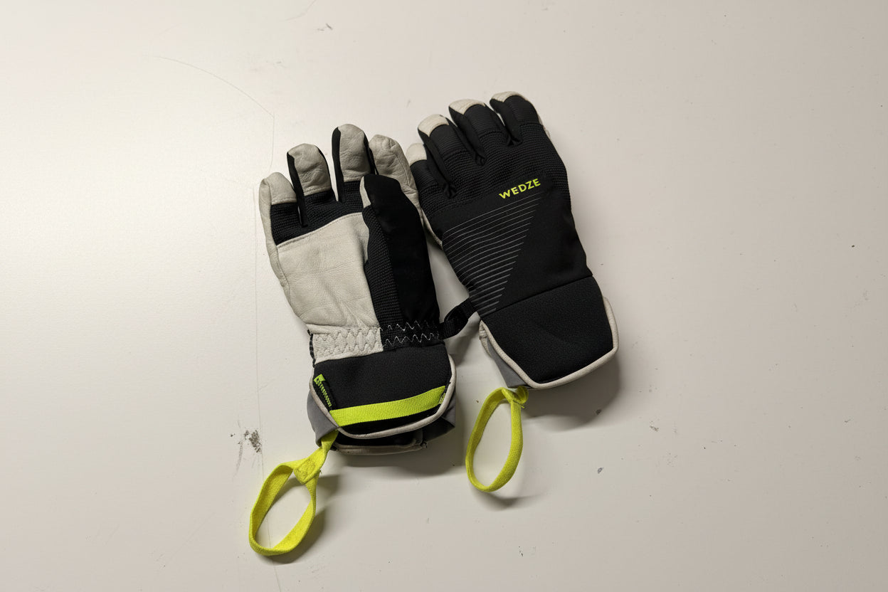 Pair of black and gray gloves with green accents on a white surface