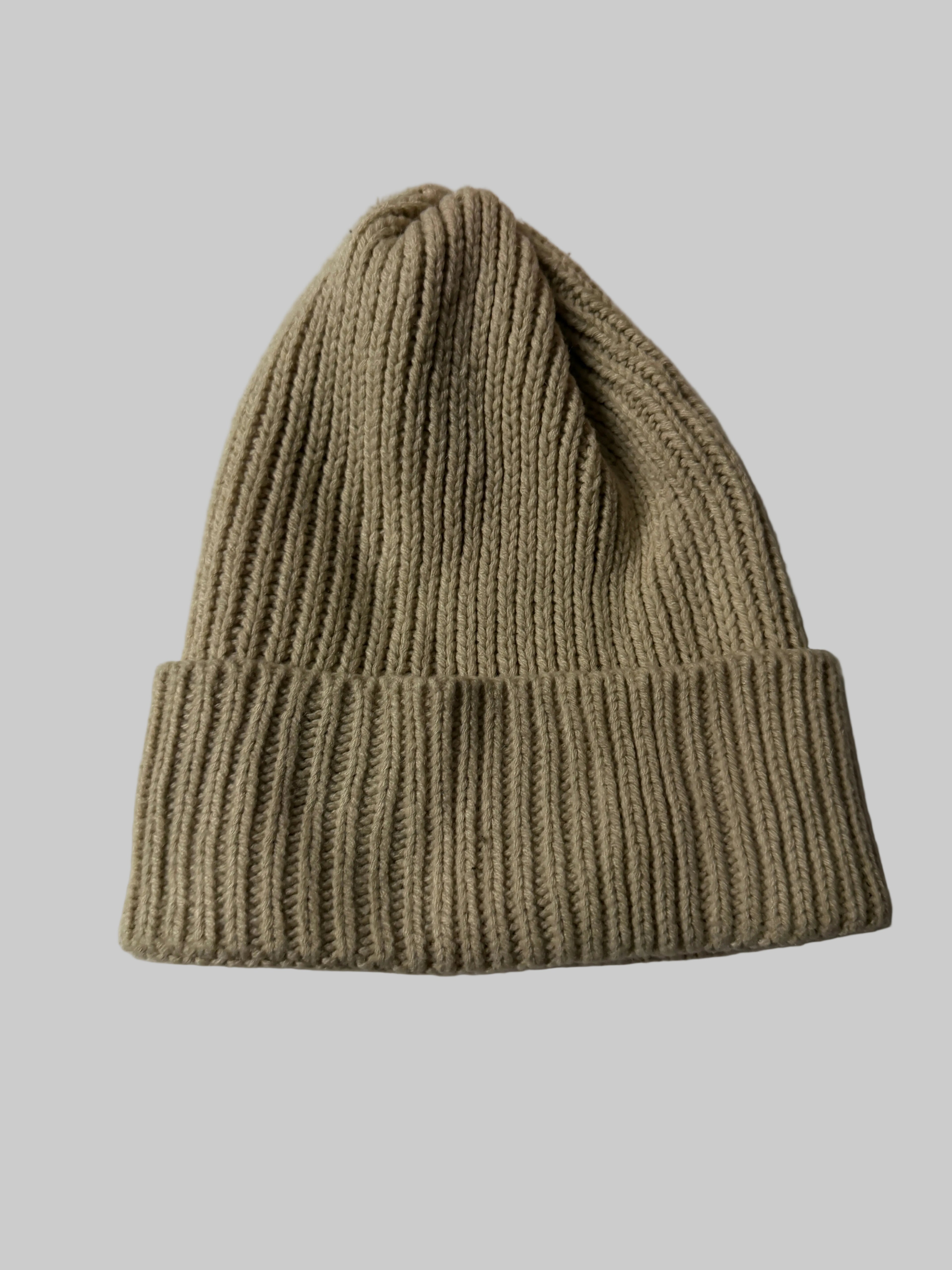 Knitted beige beanie on a white surface