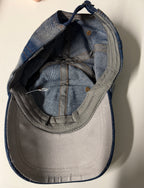 Two baseball caps, one blue and one gray, on a white surface.