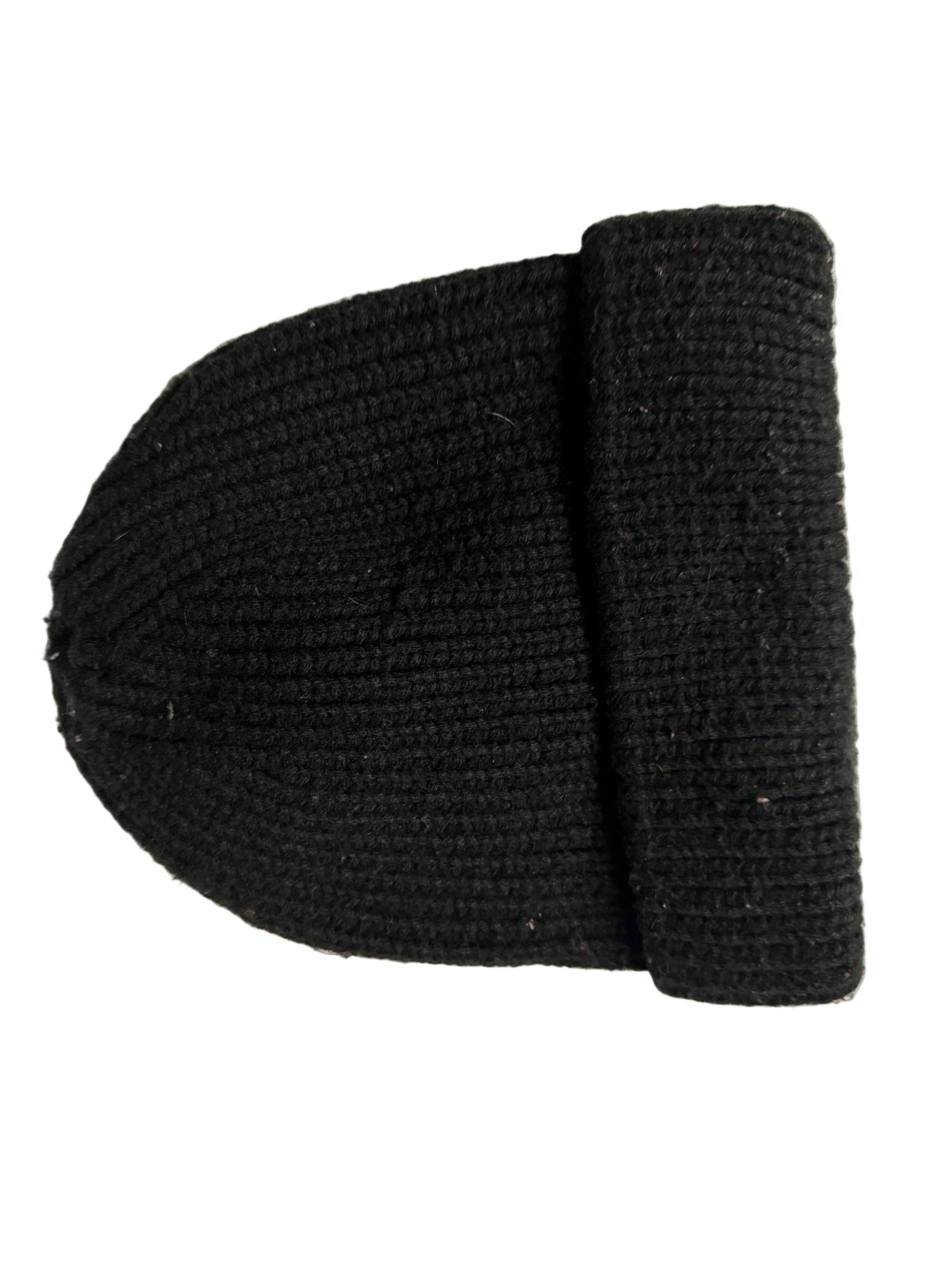 Black knit beanie with a brown logo tag on a white surface KU 7307