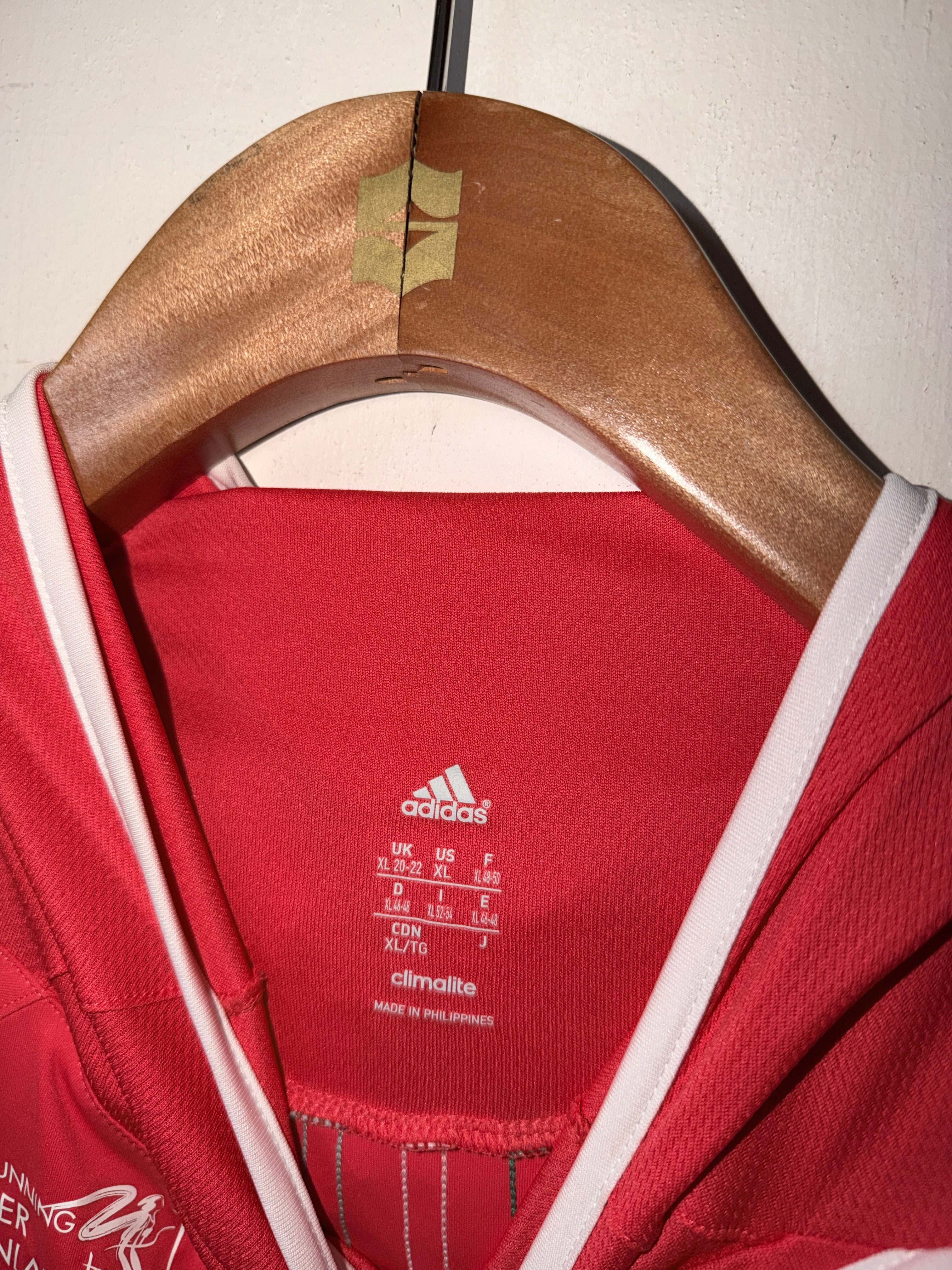 Red Adidas jacket with a gold clasp on a light background