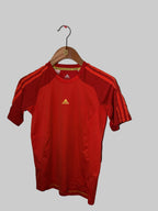 Red sports jersey with a logo on a hanger against a white wall.