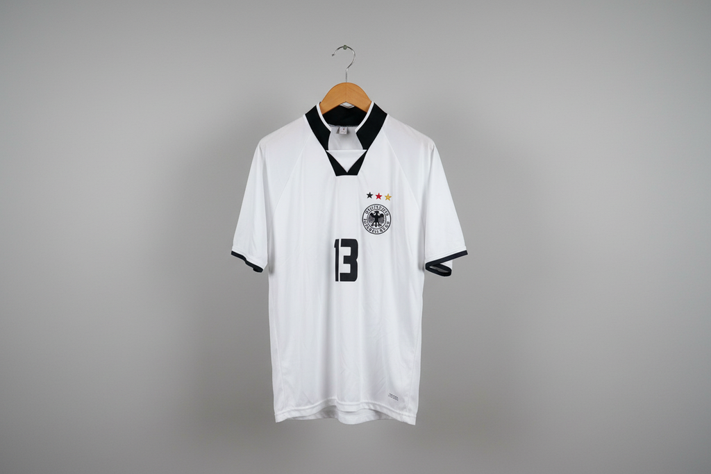 White soccer jersey with black accents on a hanger against a gray background