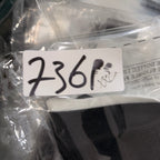 Black cap with a white tag displaying numbers, partially wrapped in clear plastic.
