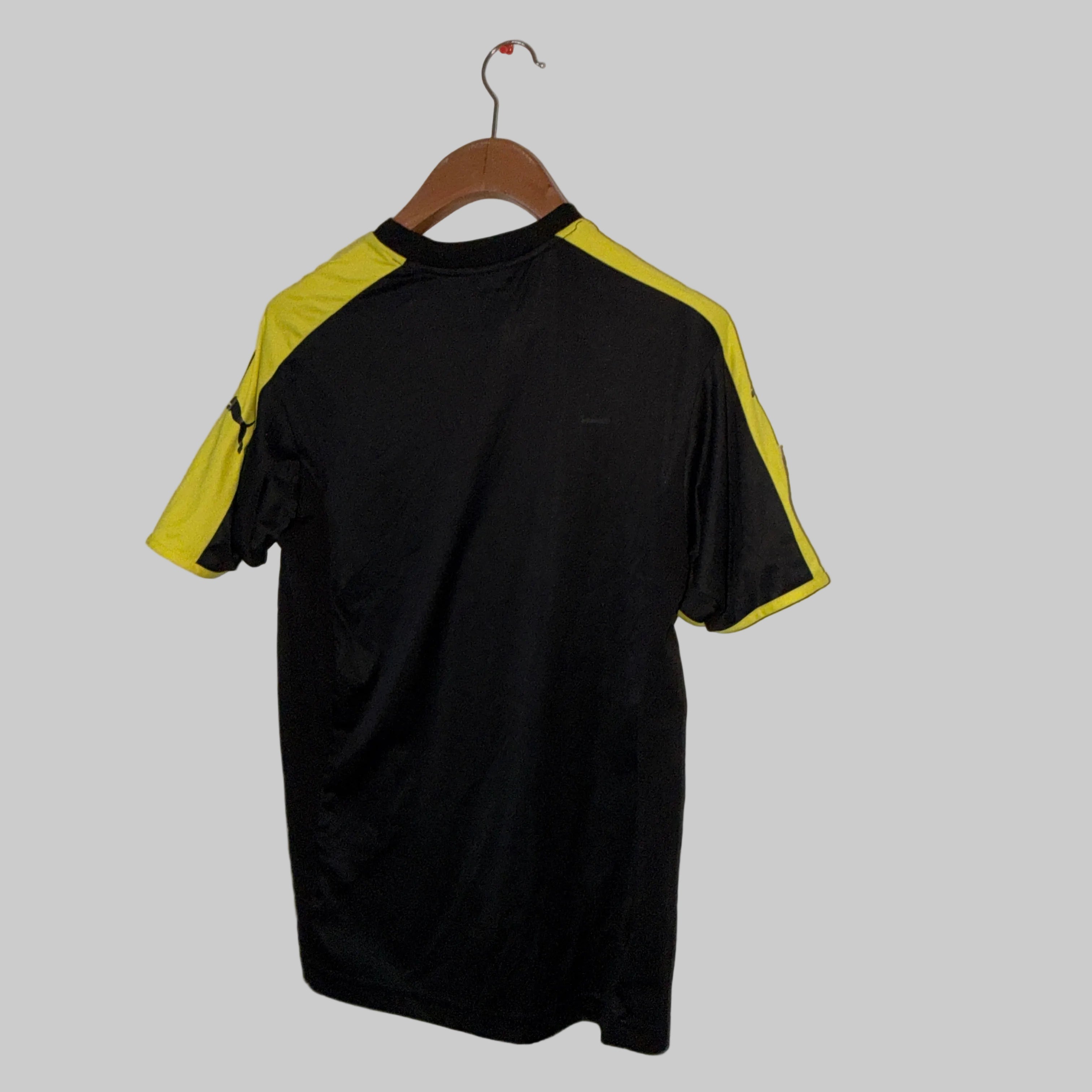 Black and yellow shirt on a hanger against a white wall.