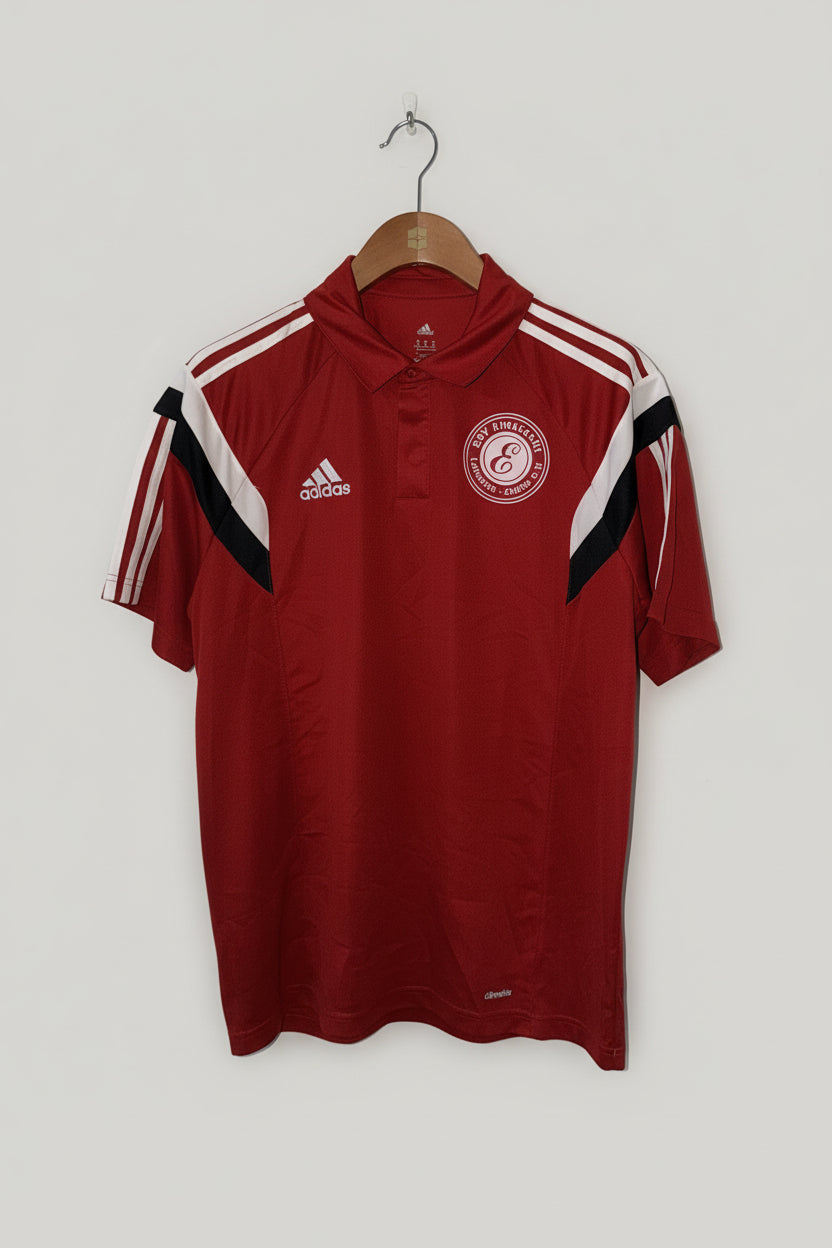 Red sports jersey with Adidas logo and additional branding on a hanger against a white wall.