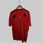 Red Adidas sports shirt on a hanger against a white wall.