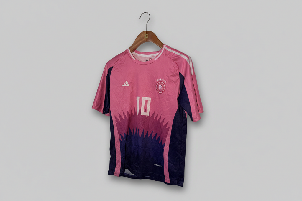 Pink and black sports jersey with Adidas logo on a hanger against a gray background