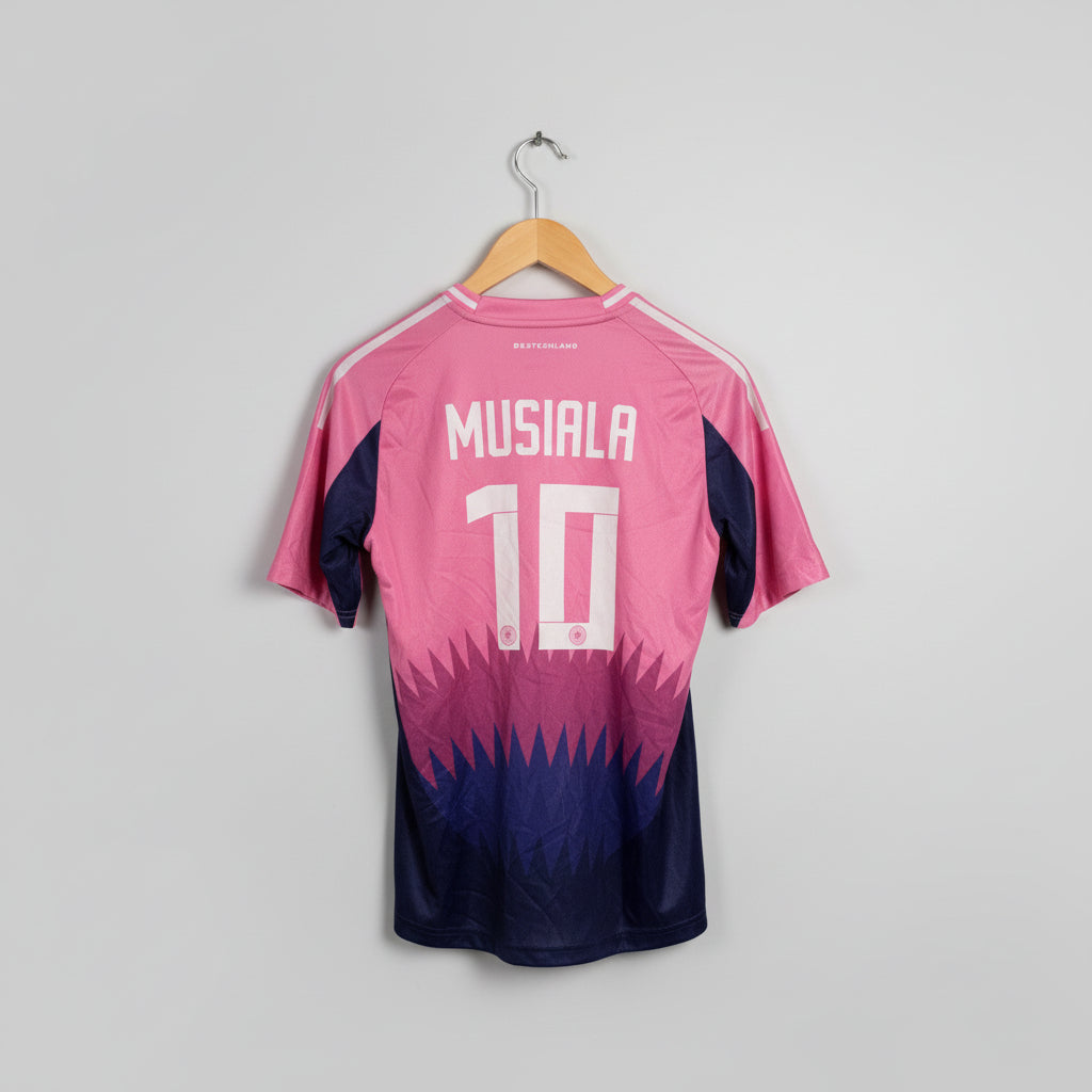Pink and blue sports jersey with 'Musiala 10' printed on it, hanging on a wooden hanger against a white wall.