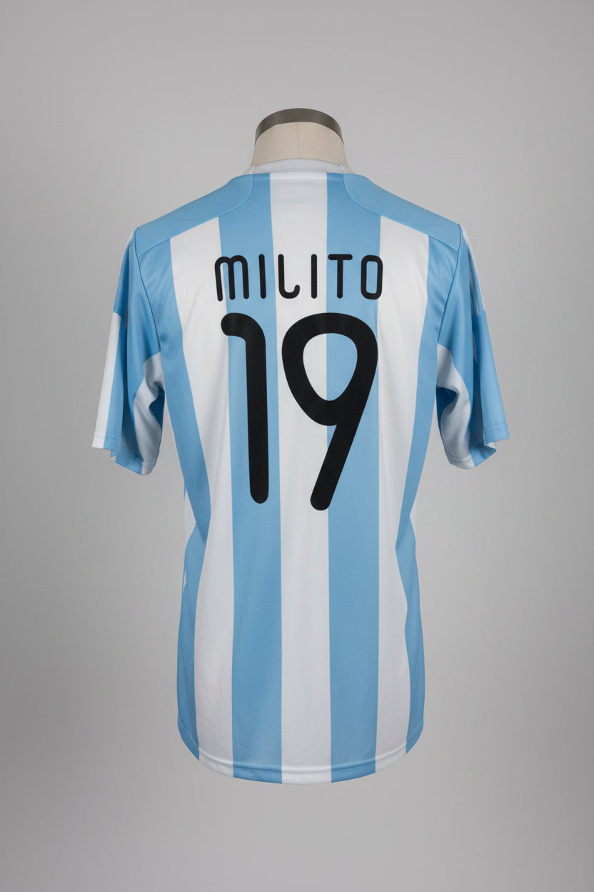 Blue and white striped sports jersey with 'Milito 19' on a hanger against a white wall.