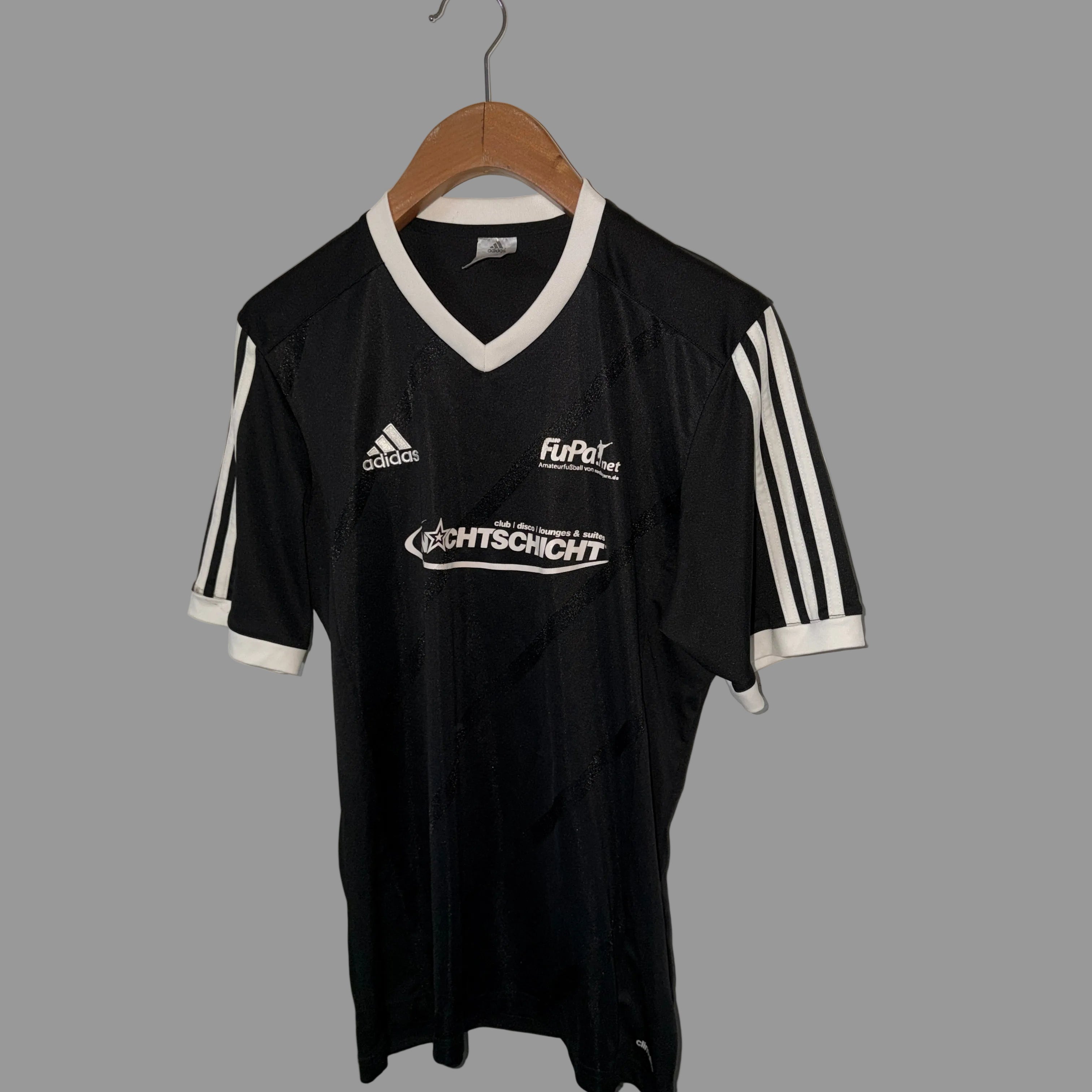 Black sports jersey with visible branding on a hanger against a white wall.