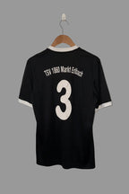 Black sports jersey with 'TSV 1860 Markt Erlbach' and number '3' on a hanger against a white wall.