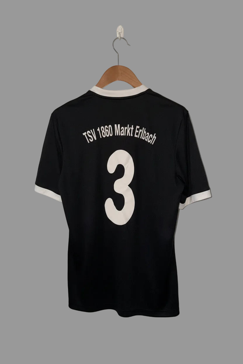Black sports jersey with 'TSV 1860 Markt Erlbach' and number '3' on a hanger against a white wall.