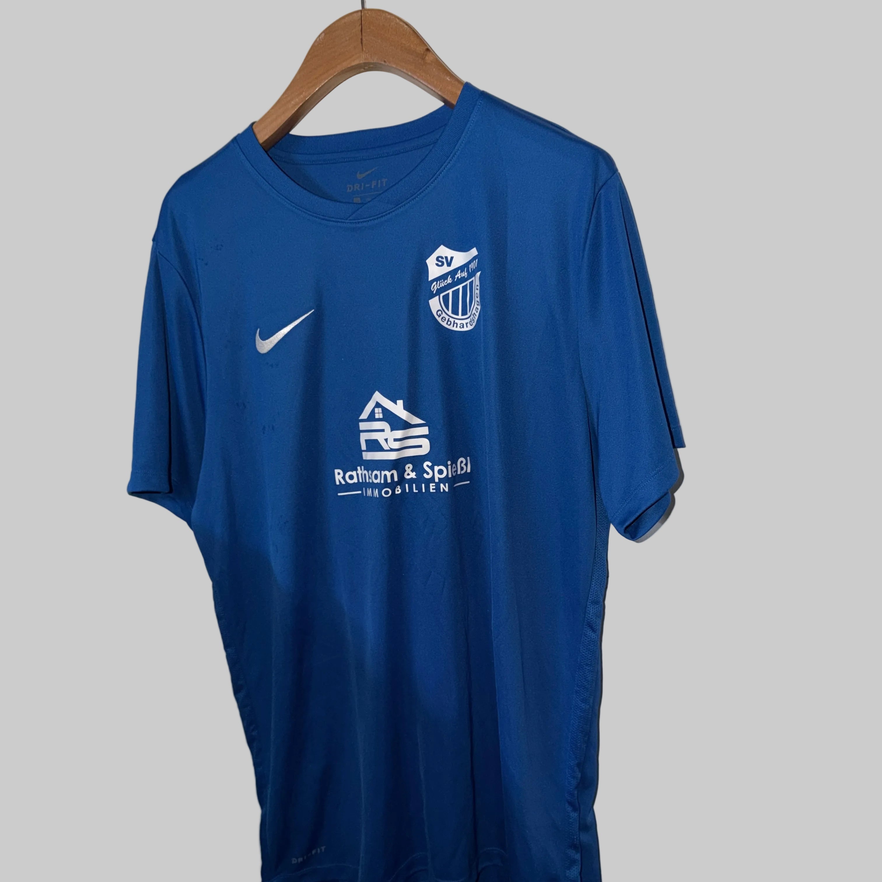 Blue sports jersey with logos on a hanger against a white wall