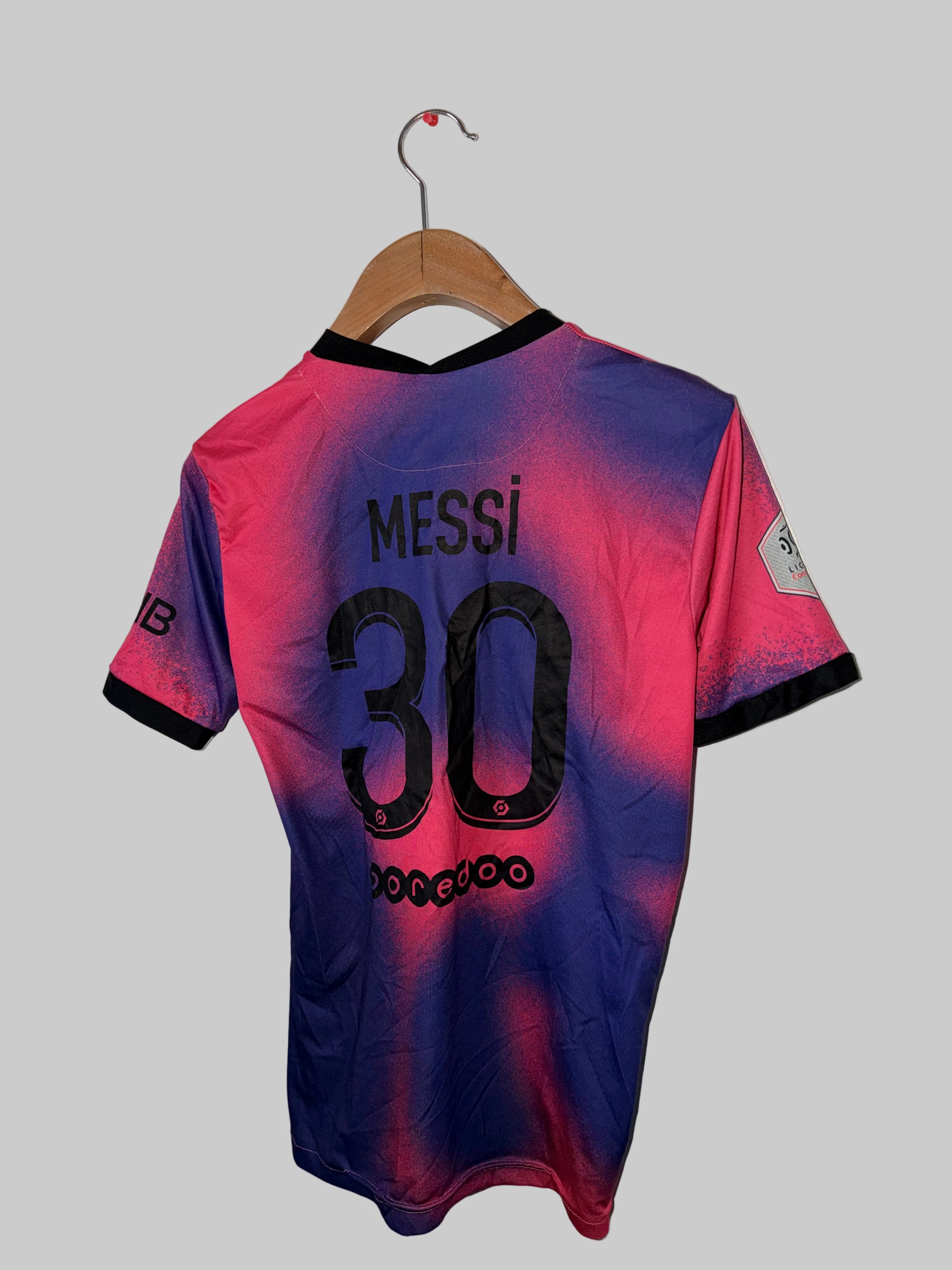 Pink and blue sports jersey with 'Messi 30' printed on it, hanging against a white wall.