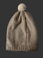 Silver glittery beanie with a pom-pom on a white surface