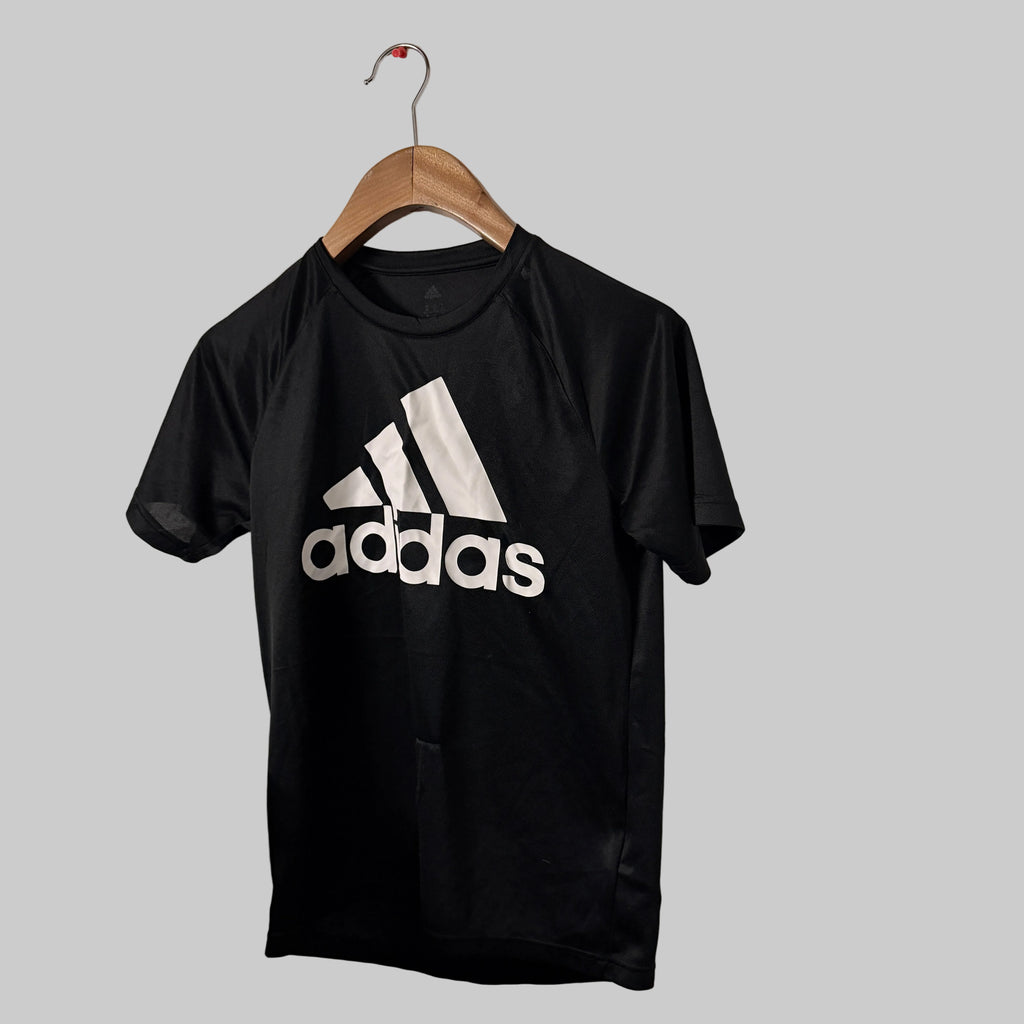 Black Adidas t-shirt on a hanger against a gray background