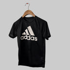 Black Adidas t-shirt on a hanger against a gray background
