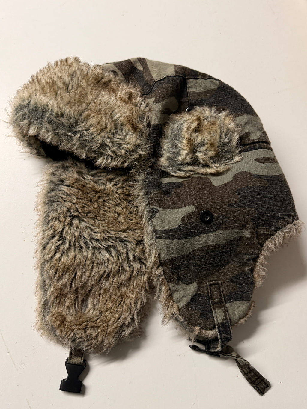 Camouflage hat with fur trim on a light background