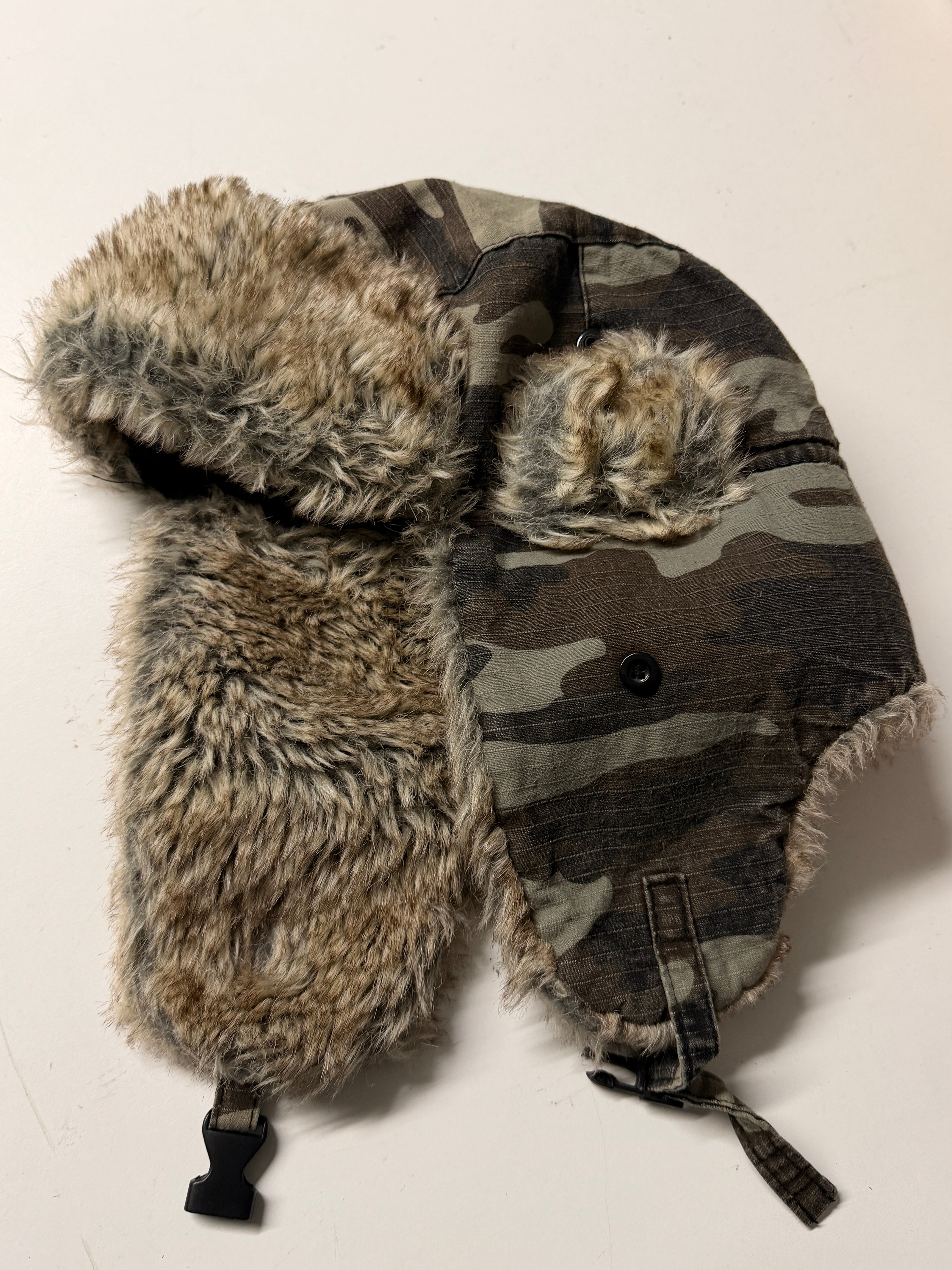 Camouflage hat with fur trim on a light background