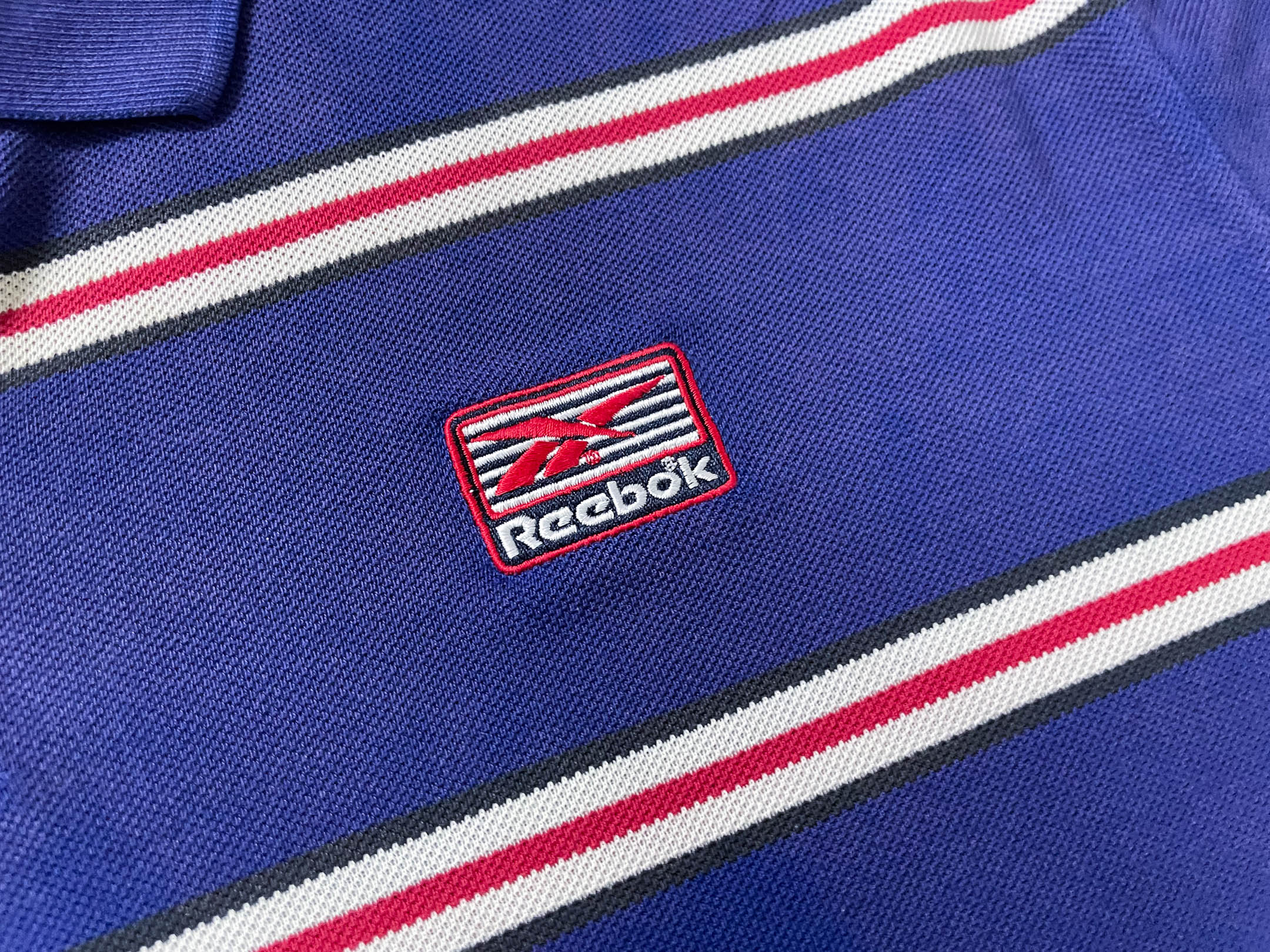 Vintage Men's Reebok Athletics Dept. Blue stripe polo shirt in M|L28 W20|SKU 4140