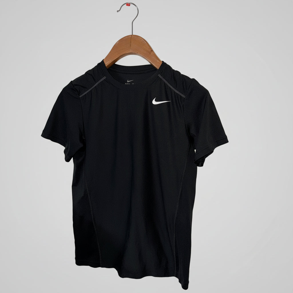 Black Nike t-shirt on a wooden hanger against a white wall.