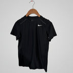 Black Nike t-shirt on a wooden hanger against a white wall.