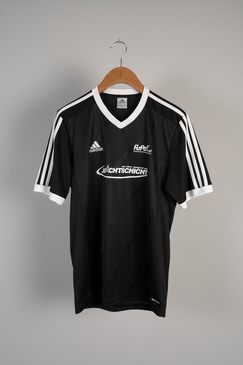 Black sports jersey with visible branding on a hanger against a white wall.