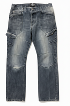 A pair of dark blue denim cargo jeans with a heavily faded, washed finish,